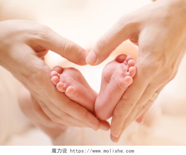 两只手抓着新生儿的脚丫特写小刚出生的婴儿脚在雌鼠心脏形手特写